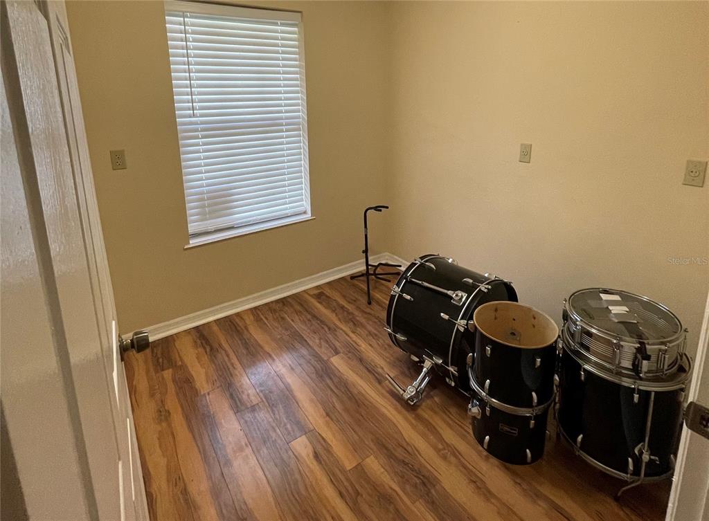 A small room with wood-look flooring and a drum set near a window — 6611 SW 80TH AVENUE, OCALA, FL