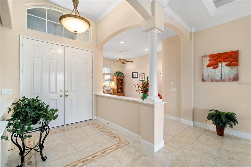 A bright foyer features tile flooring, double entry doors, and an arched opening to a room — 1023 RAINBOW COURT, BRADENTON, FL