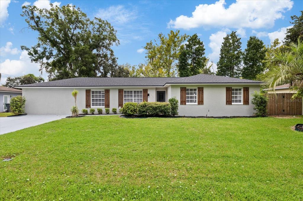 A single-story house with a gray exterior, dark roof, and a large front lawn — 3417 LORI LANE S, LAKELAND, FL