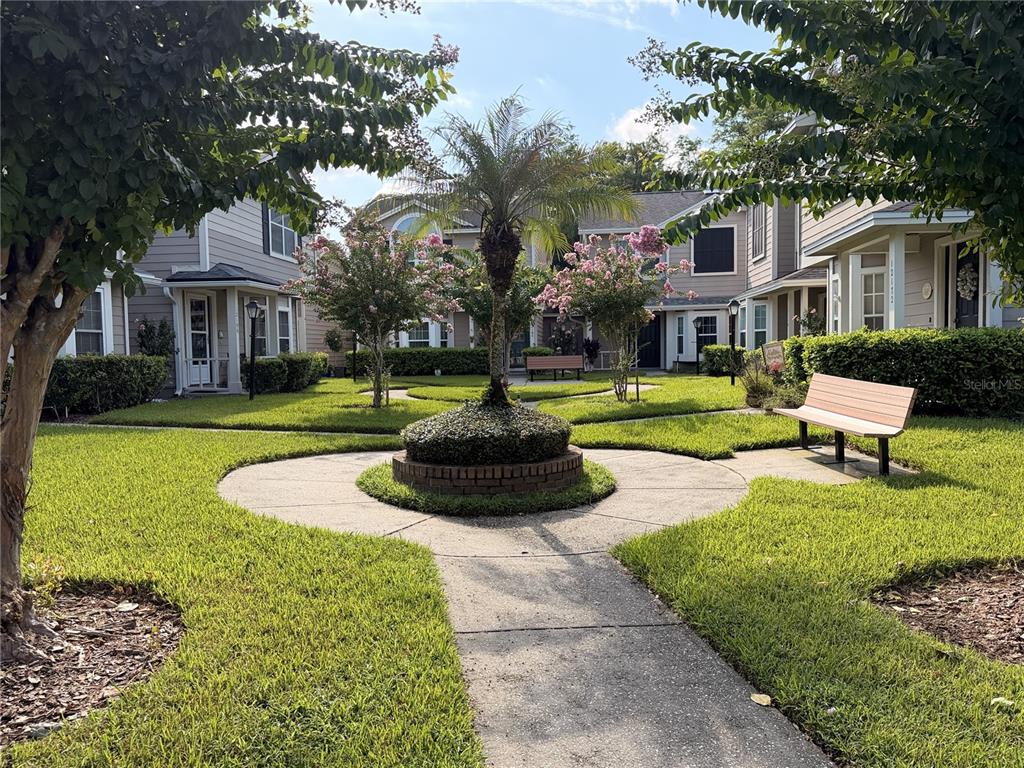 A multi-unit residential building with tan siding, a white fence, and a landscaped front lawn — 12192 SHADY SPRING WAY, ORLANDO, FL