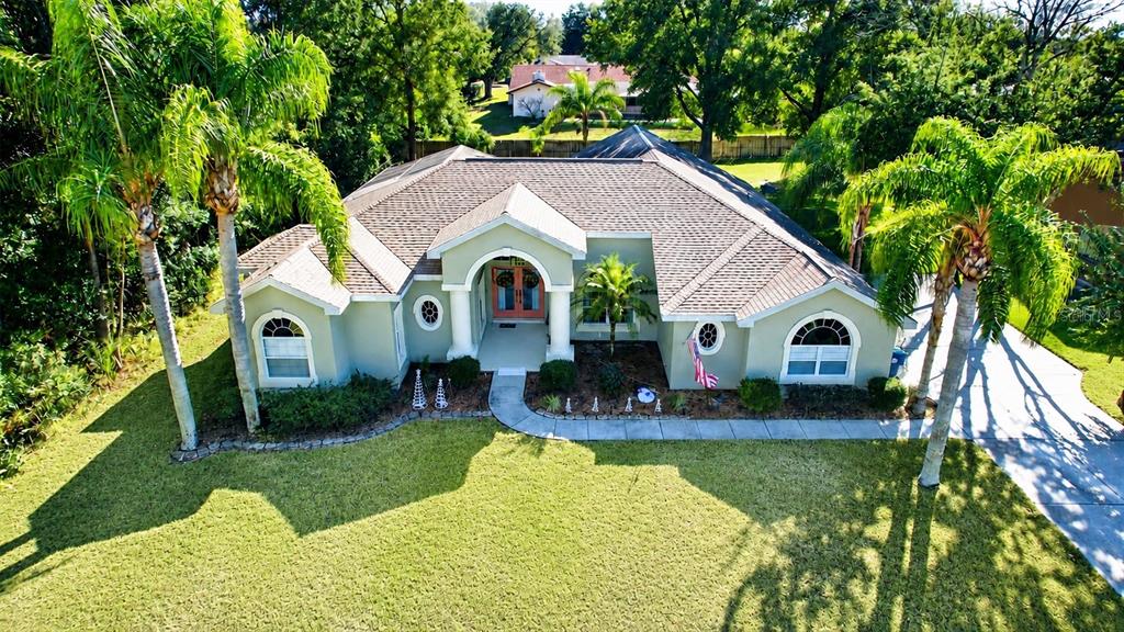 An aerial view of a single-story house with a light green exterior and palm trees — 7552 RIVER COUNTRY DRIVE, WEEKI WACHEE, FL