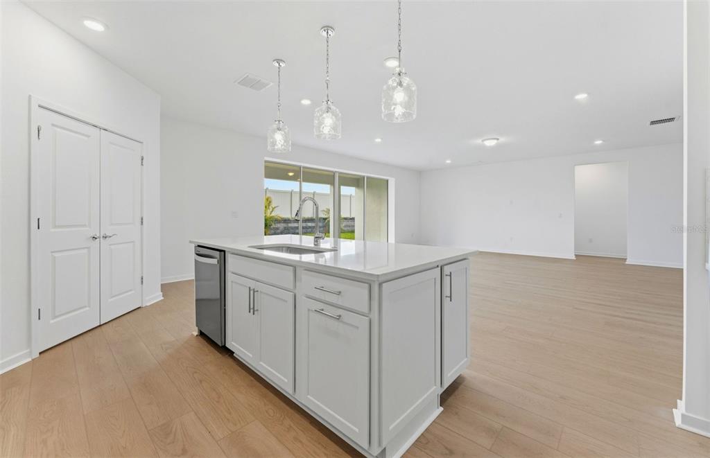 A bright kitchen features white cabinetry, a central island, stainless steel appliances, and light flooring — 9738 AUTUMN RIDGE AVENUE, RIVERVIEW, FL