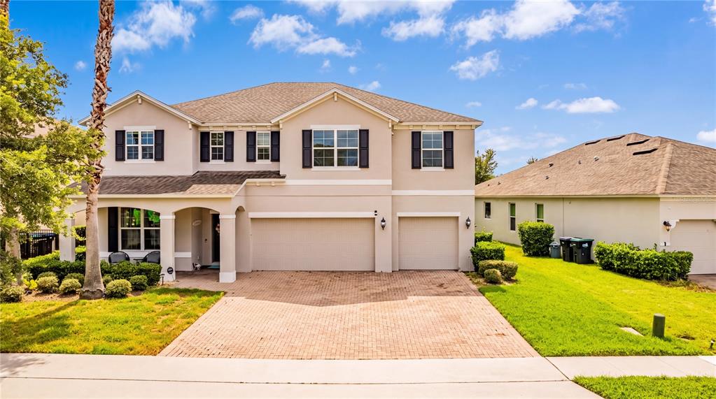 A two-story suburban house features a beige stucco exterior, a three-car garage, and palm trees — 12225 STONE BARK TRAIL, ORLANDO, FL