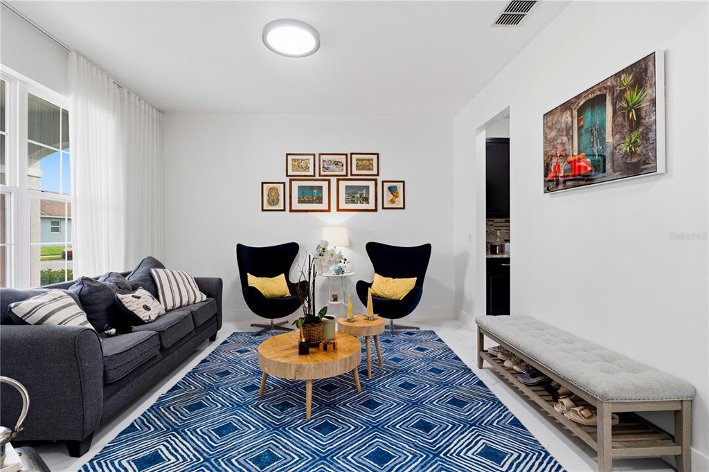 A living room features a blue geometric rug, a wooden console table, and a bench — 12225 STONE BARK TRAIL, ORLANDO, FL
