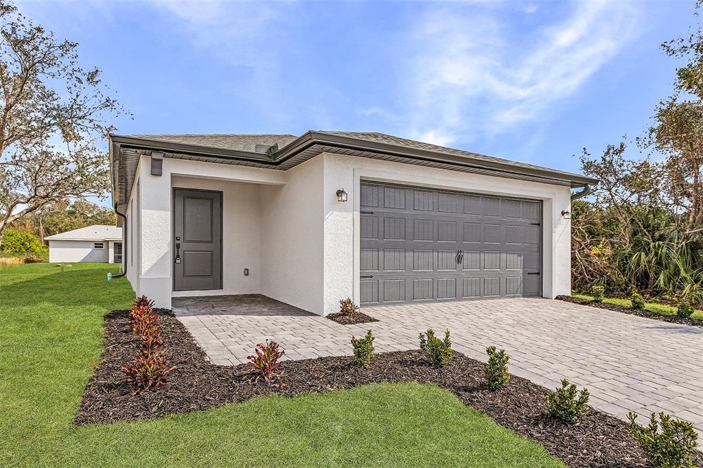 A single-story house with a white stucco exterior, gray garage door, and a paved driveway — 3418 EAGLE PASS STREET, NORTH PORT, FL