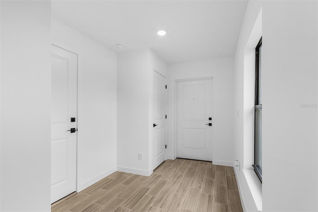 A bright entryway features white walls, light wood-look tile flooring, and three white doors — 3418 EAGLE PASS STREET, NORTH PORT, FL