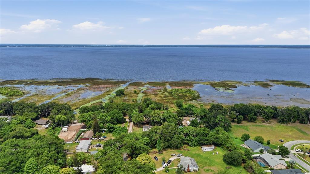 An aerial view shows a residential neighborhood situated along the shore of a large lake — 4791 SUNSET ROAD, ST CLOUD, FL