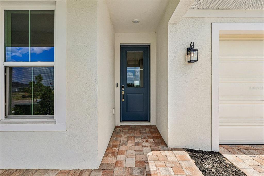 A blue front door is centered between a window and a garage on a paved porch — 5024 SALADO DRIVE, ST CLOUD, FL