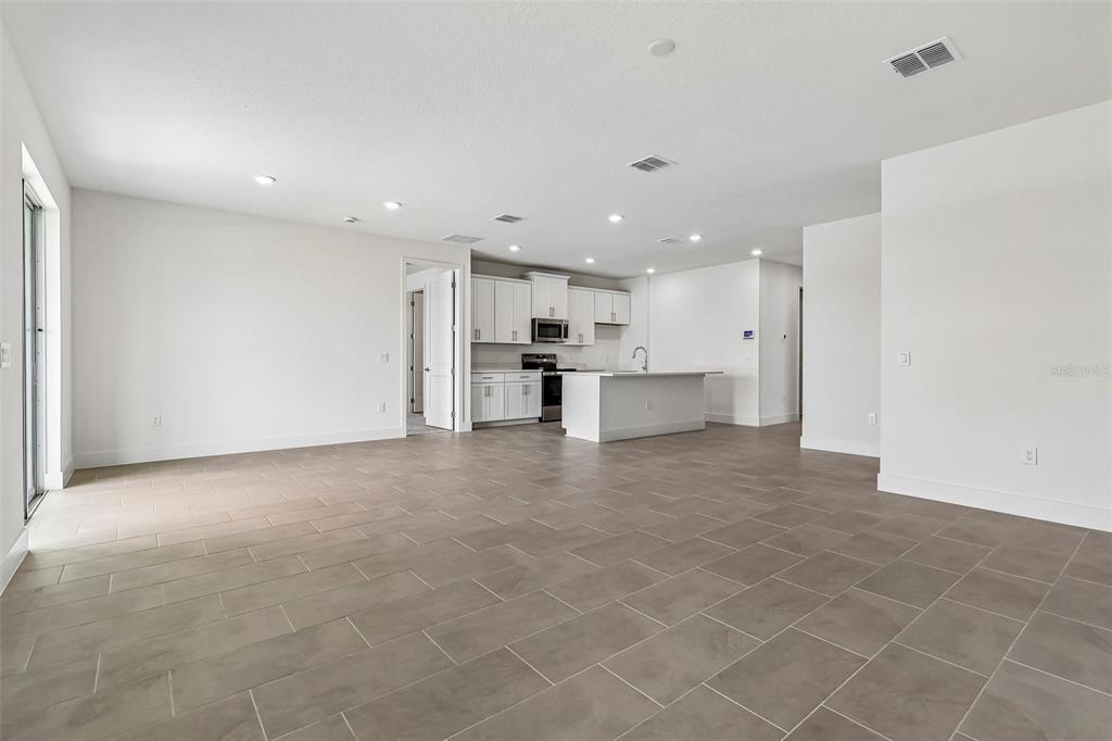An open-concept kitchen and living area features white cabinetry, a central island, and tile flooring — 5024 SALADO DRIVE, ST CLOUD, FL