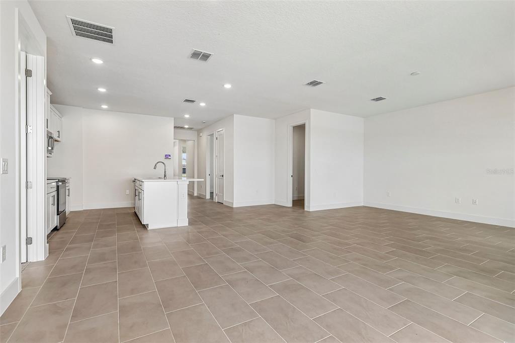 An open-concept kitchen and living area features white cabinetry, a kitchen island, and tile flooring — 5024 SALADO DRIVE, ST CLOUD, FL