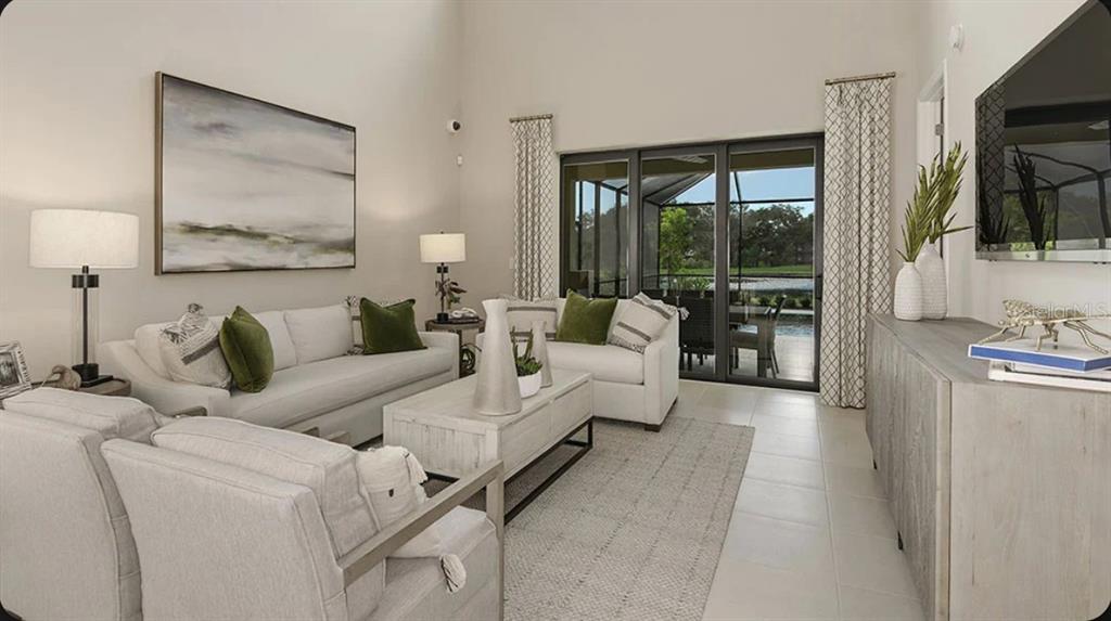A bright living room features light-colored sofas, a wooden coffee table, and sliding glass doors — 5079 LOST KEY PLACE, ST CLOUD, FL