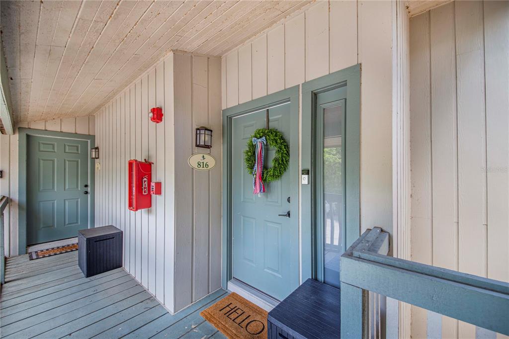 An exterior view of a covered apartment entryway with a blue door and wreath — 816 PINEWOOD COURT UNIT 3126, HAINES CITY, FL