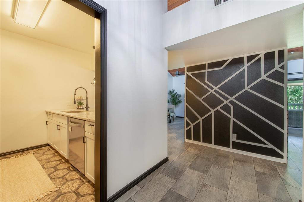 A view of a kitchen area and a hallway featuring a geometric accent wall — 816 PINEWOOD COURT UNIT 3126, HAINES CITY, FL