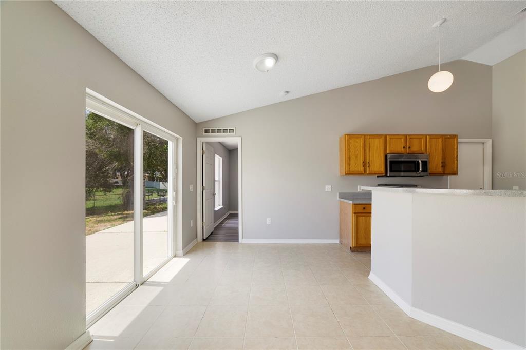 A dining area with tile floors, a sliding glass door, and an open kitchen — 529 PEACE DRIVE, POINCIANA, FL