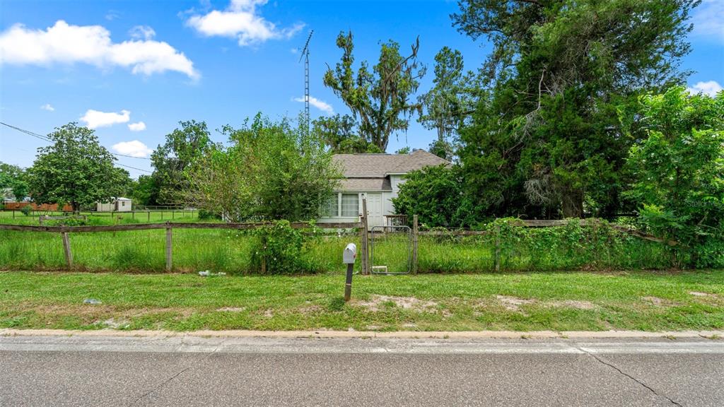 A small, light-colored house sits behind a wooden fence and overgrown lawn — 5698 NAVARRE AVENUE, HAMPTON, FL