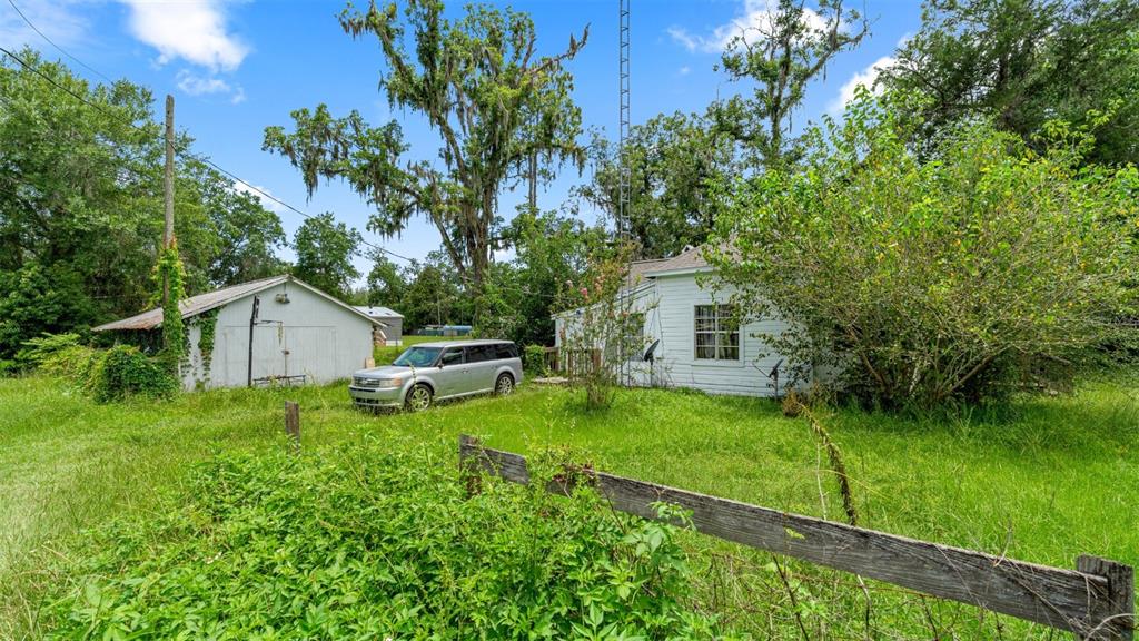 A white house and detached garage sit on a grassy lot with a wooden fence — 5698 NAVARRE AVENUE, HAMPTON, FL