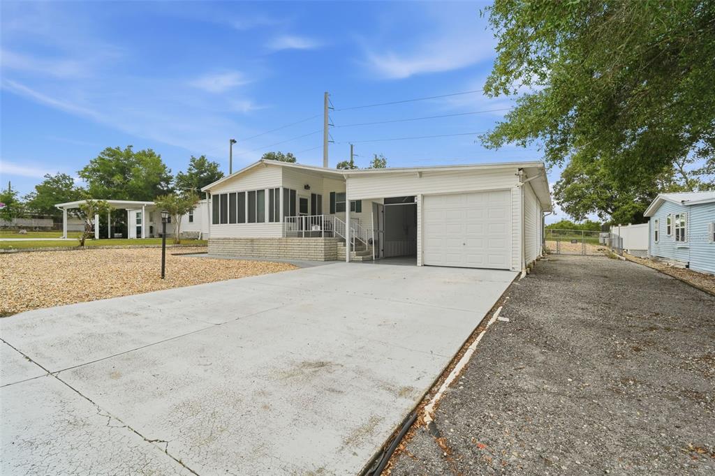 A single-story manufactured home features a white exterior, a screened porch, and a concrete driveway — 30 FLORENCE BOULEVARD, DEBARY, FL