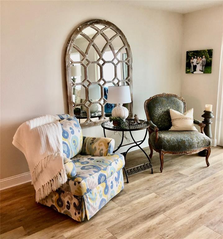 A living room features two armchairs, a small round table with a lamp, and a mirror — 7 DUNOON PLACE UNIT 203, DUNEDIN, FL