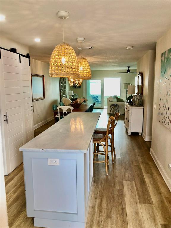 A kitchen island with light blue cabinetry sits in front of a dining area — 7 DUNOON PLACE UNIT 203, DUNEDIN, FL