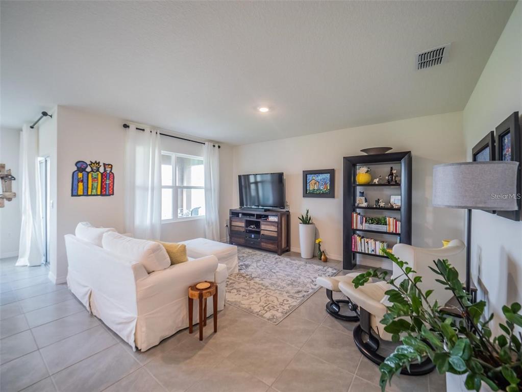 An open-concept living room and kitchen featuring white cabinetry, tile flooring, and a neutral sofa — 4885 PANGA AVENUE, MOUNT DORA, FL