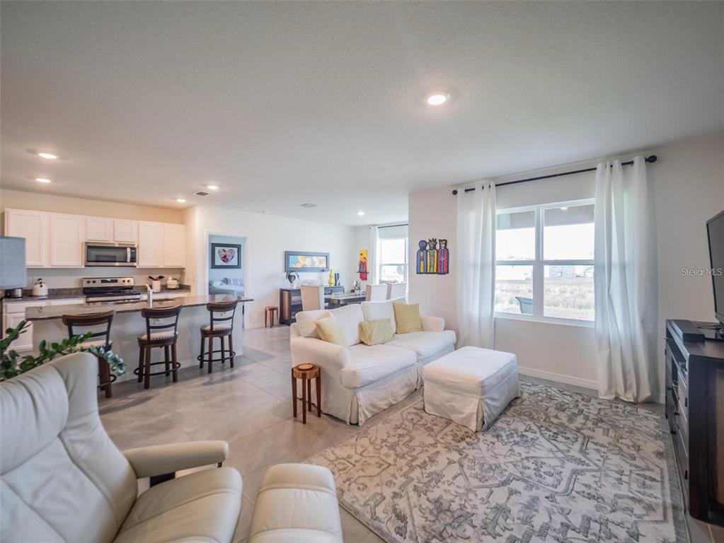 A kitchen features white cabinets, granite countertops, a center island, and stainless steel appliances — 4885 PANGA AVENUE, MOUNT DORA, FL