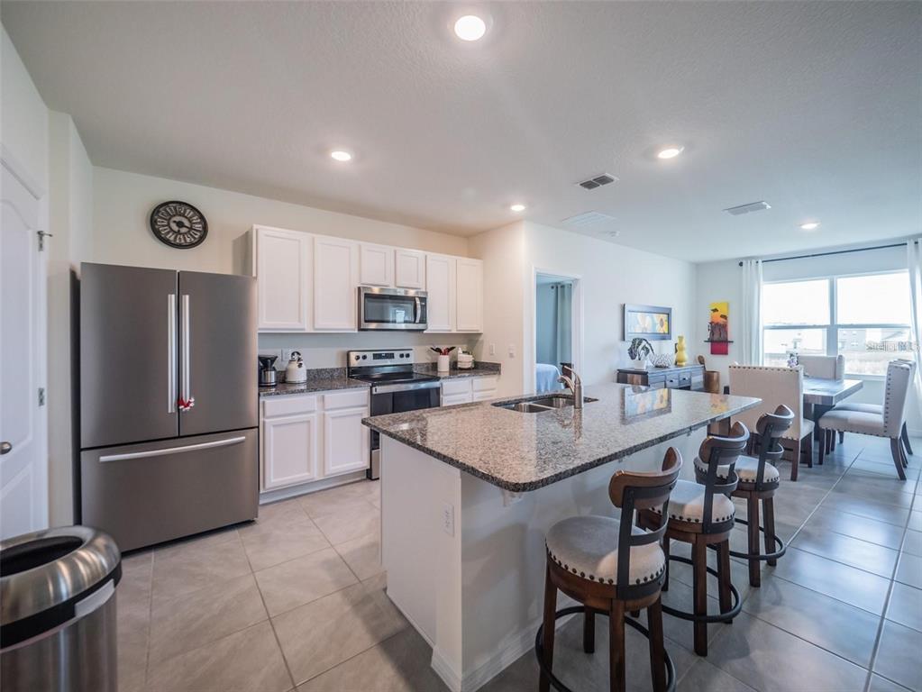 A living room features a white sofa, a television on a wooden stand, and a bookshelf — 4885 PANGA AVENUE, MOUNT DORA, FL