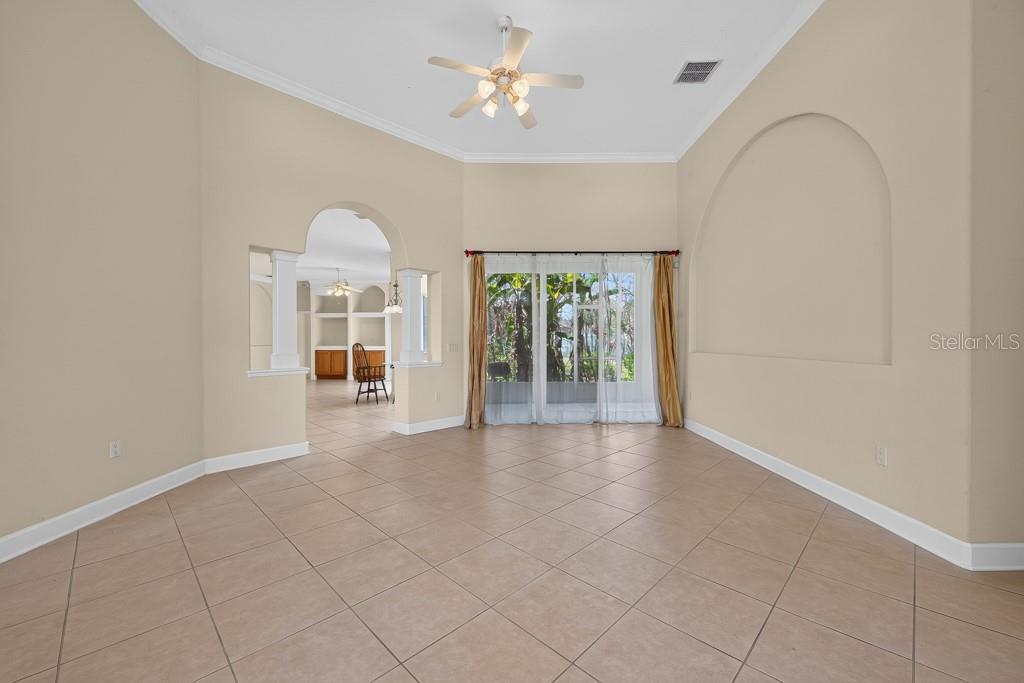 A spacious living room with tile flooring, a ceiling fan, and an arched wall niche — 306 TERRANOVA BOULEVARD, WINTER HAVEN, FL