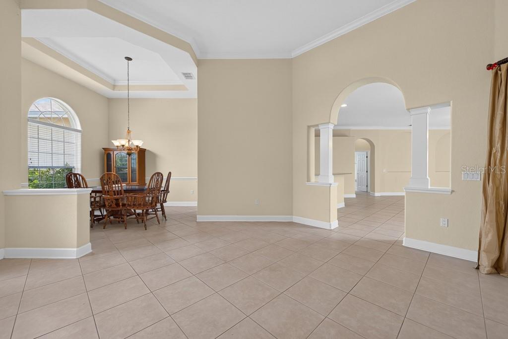 A dining area with a tray ceiling and tile floors opens into a living space — 306 TERRANOVA BOULEVARD, WINTER HAVEN, FL