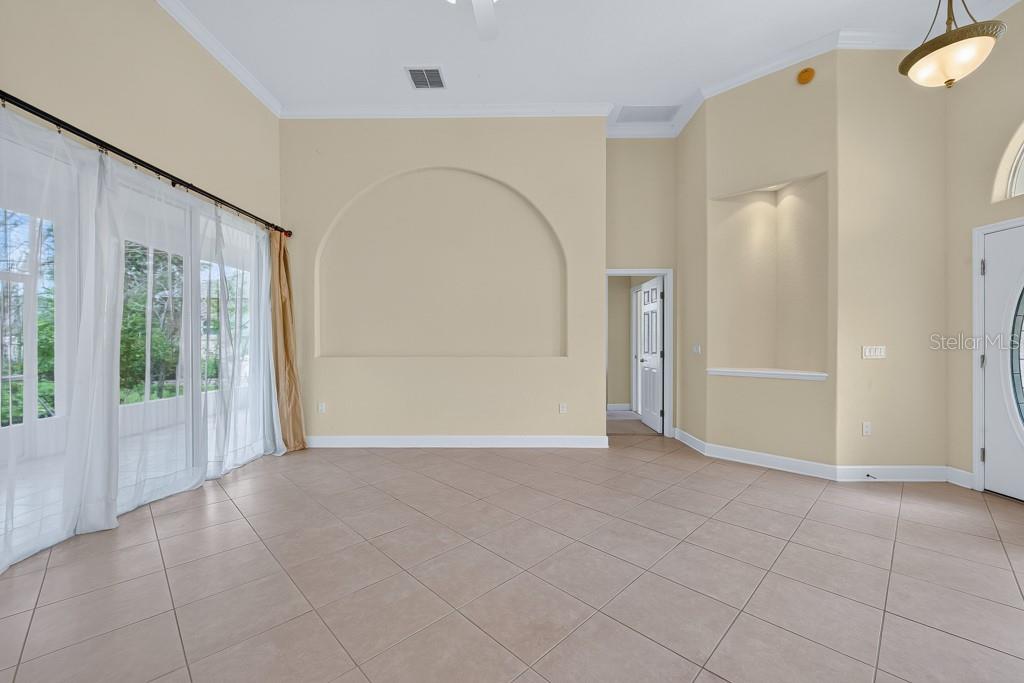 A living room features beige tile floors, a large arched wall niche, and glass doors — 306 TERRANOVA BOULEVARD, WINTER HAVEN, FL