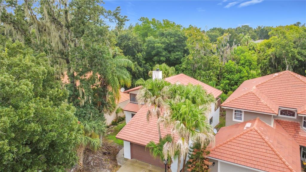 An aerial view shows two houses with terracotta tile roofs surrounded by dense green trees — 662 NIGHTHAWK CIRCLE, WINTER SPRINGS, FL