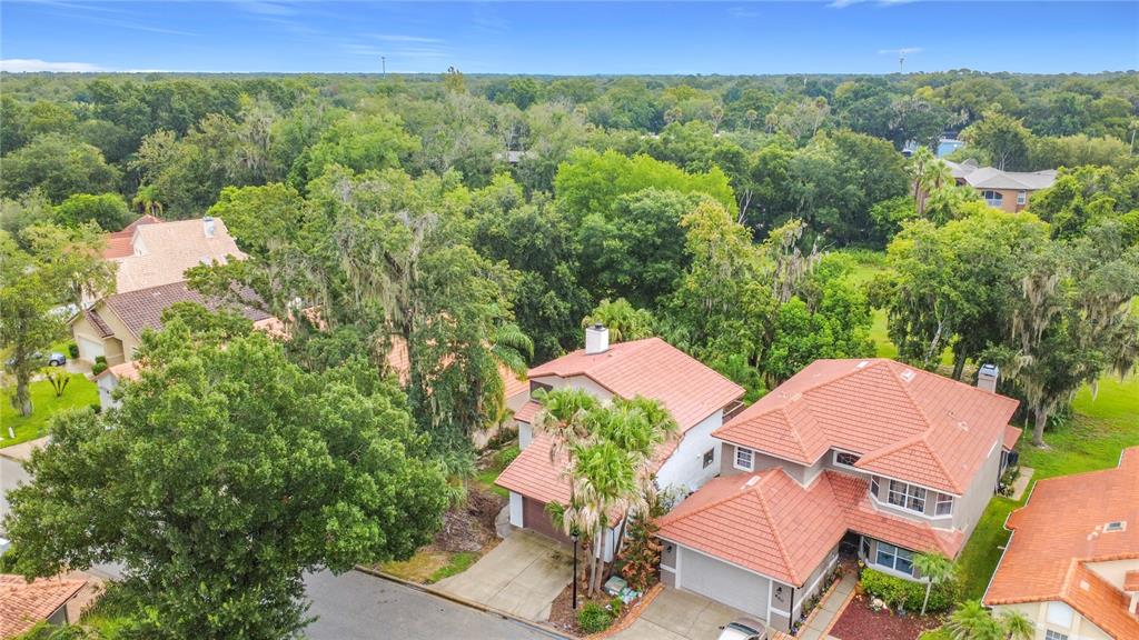 An aerial view shows several suburban houses with red tile roofs surrounded by dense trees — 662 NIGHTHAWK CIRCLE, WINTER SPRINGS, FL