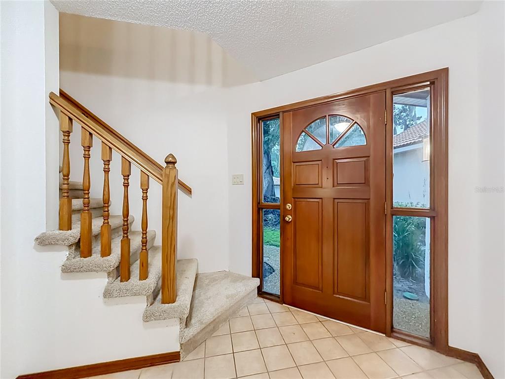 An entryway features a carpeted staircase with wooden railings and a wooden front door — 662 NIGHTHAWK CIRCLE, WINTER SPRINGS, FL