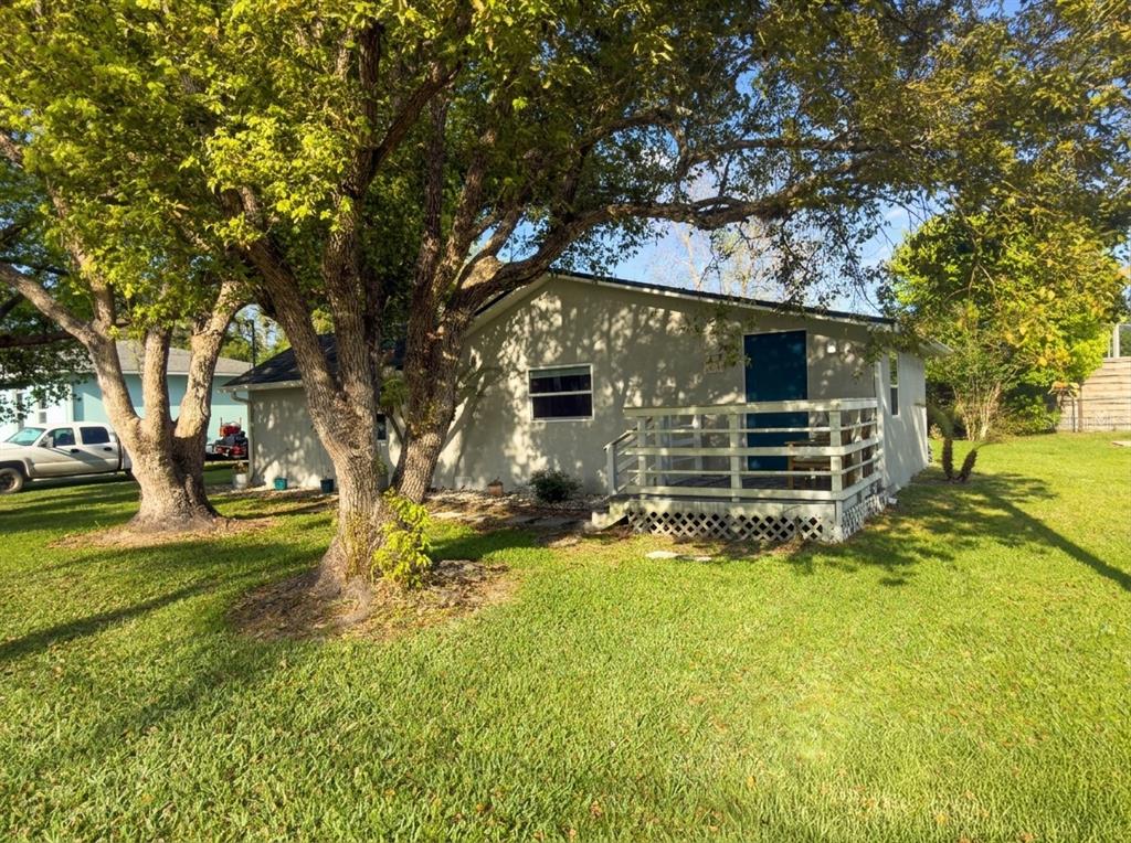 A single-story house with a wooden deck and large trees in the front yard — 1611 SALMON STREET, ST CLOUD, FL