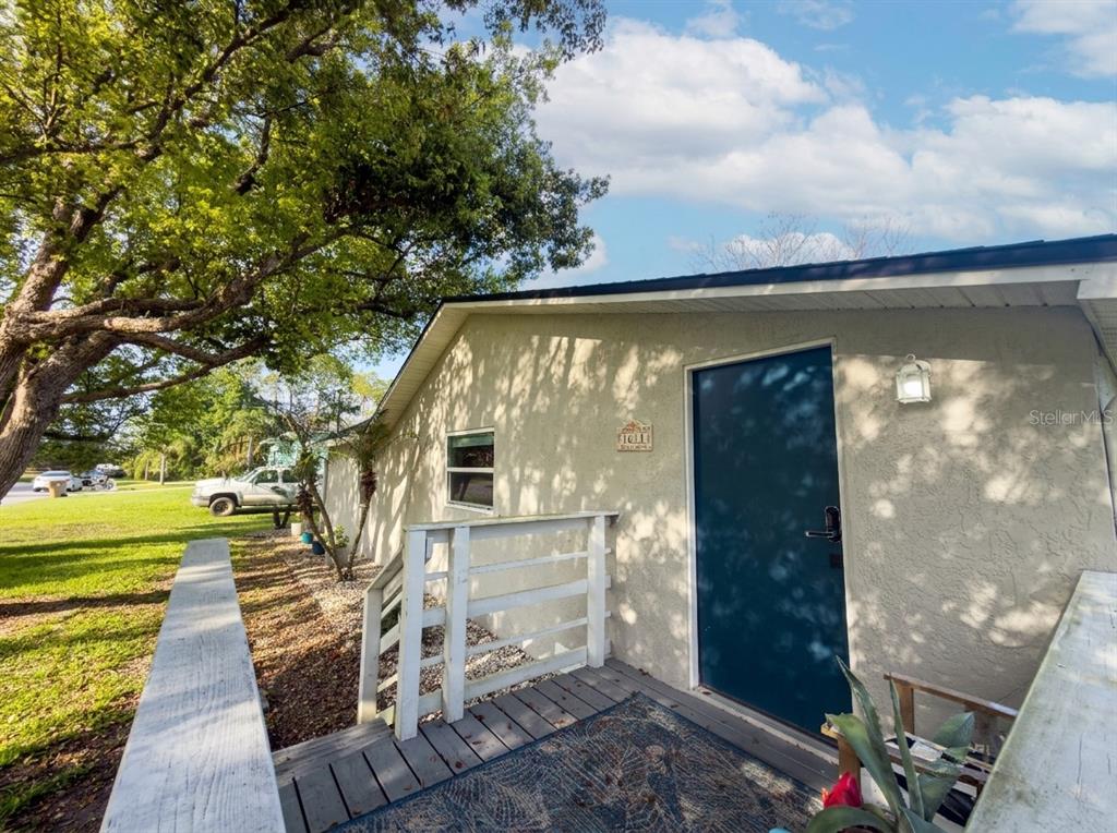 A view of a house exterior featuring a blue door, wooden deck, and white railing — 1611 SALMON STREET, ST CLOUD, FL