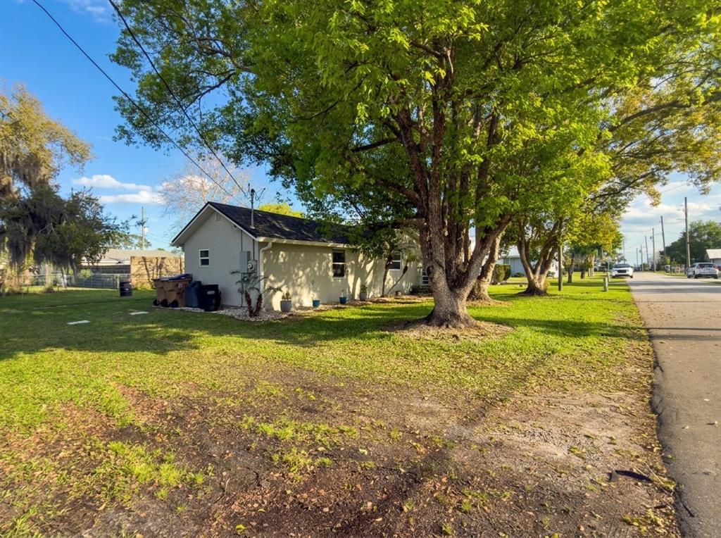 A side view of a single-story house with a large tree in the front yard — 1611 SALMON STREET, ST CLOUD, FL