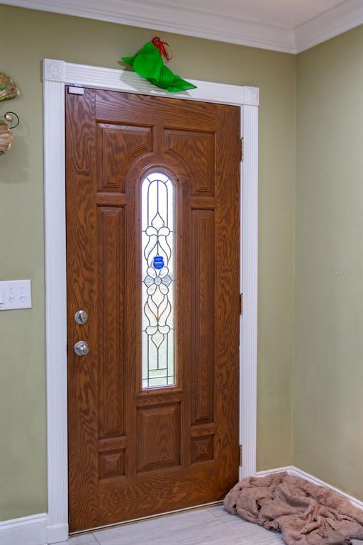 A wooden front door with a decorative glass insert is set in a white frame — 11001 N ARMENIA AVENUE, TAMPA, FL