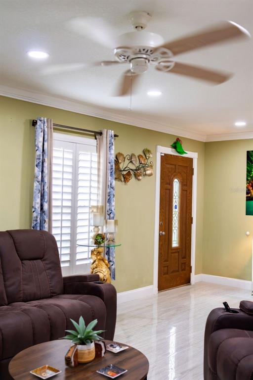 A living room features a brown recliner, a ceiling fan, and a wooden front door — 11001 N ARMENIA AVENUE, TAMPA, FL