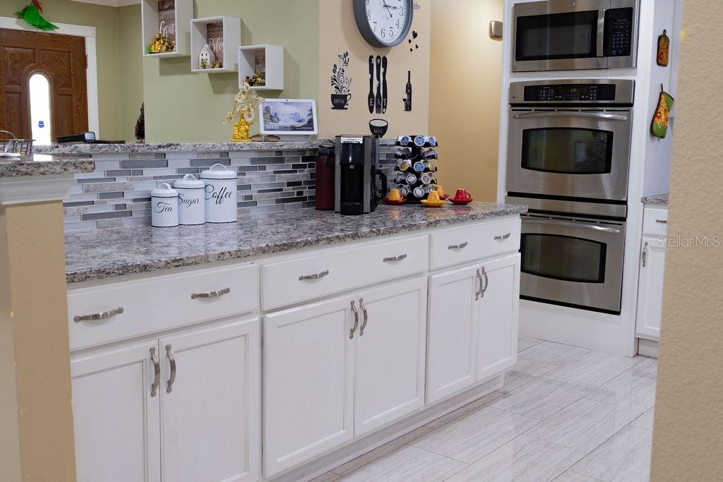 A kitchen features white cabinets, granite countertops, stainless steel appliances, and a tiled backsplash — 11001 N ARMENIA AVENUE, TAMPA, FL