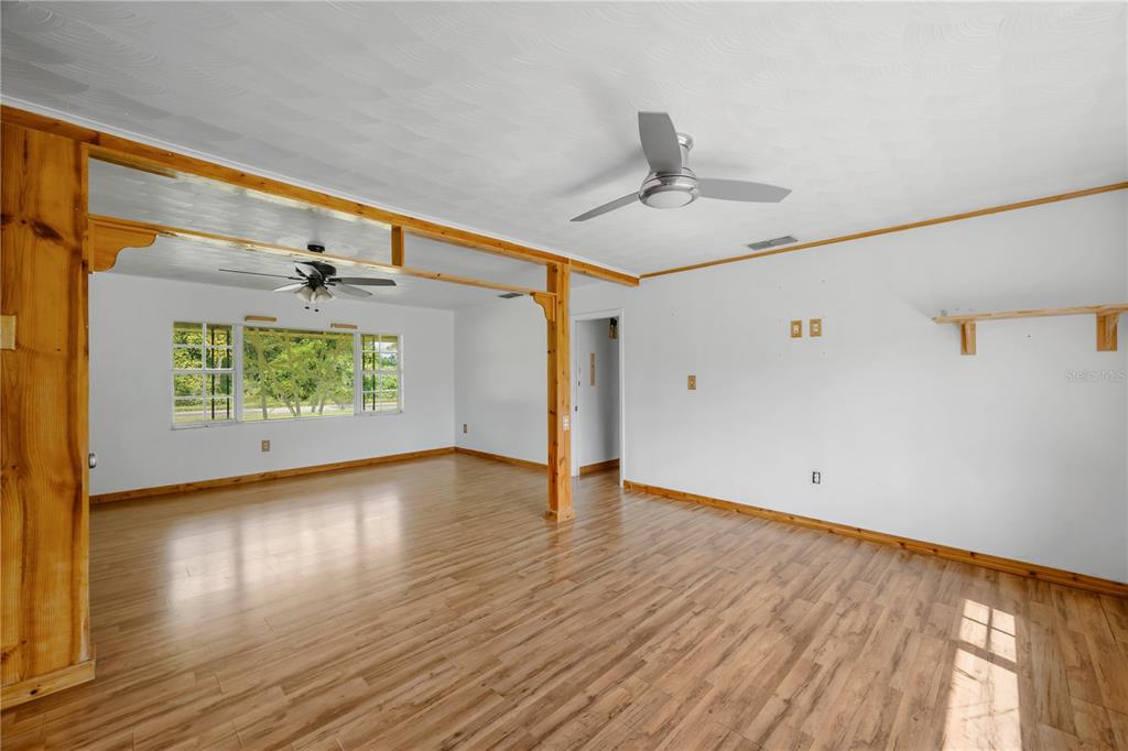 An open-concept living area features wood-look laminate flooring, white walls, and two ceiling fans — 1619 N DOVER ROAD, DOVER, FL