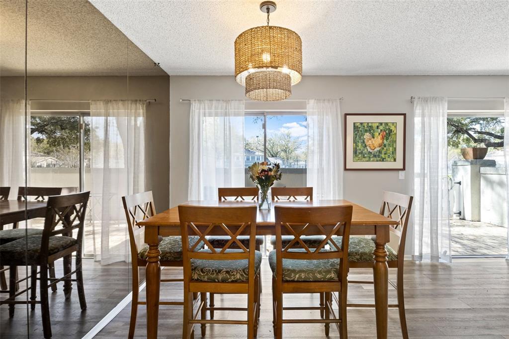 A dining room features a wooden table, six chairs, a woven pendant light, and mirrors — 6305 MORNINGMIST COURT UNIT 6305, TEMPLE TERRACE, FL