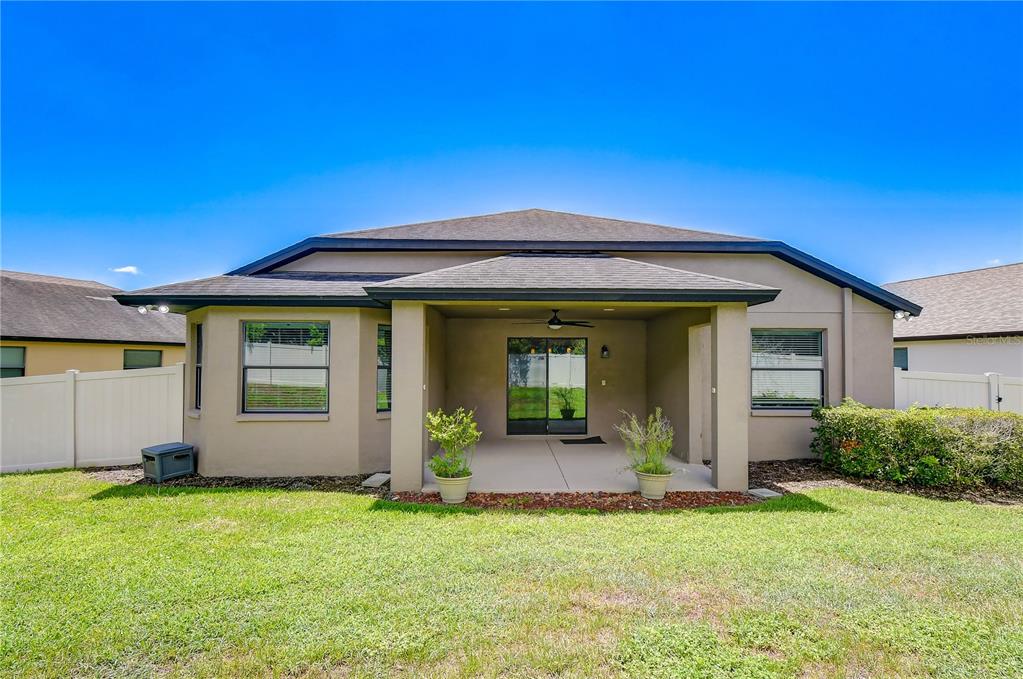 The exterior view shows the back of a house with a covered patio and lawn — 826 VINO VERDE CIRCLE, BRANDON, FL