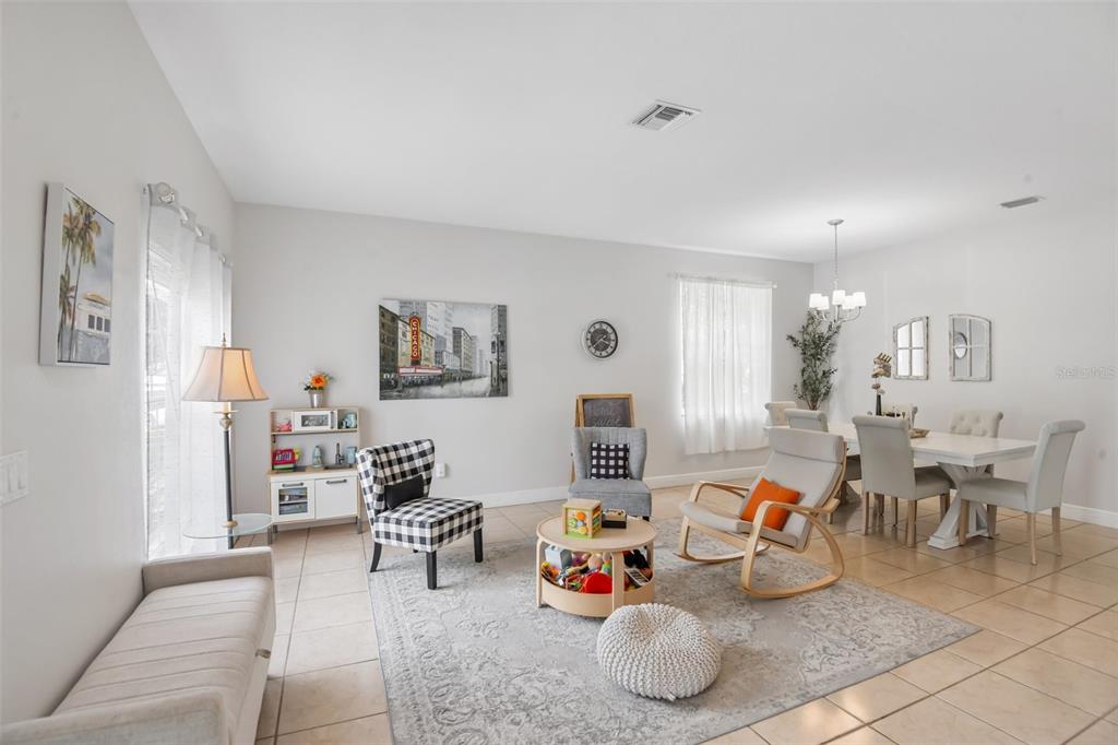 A bright, open-concept living and dining area features tile flooring, a neutral rug, and furniture — 5903 CAPE LOOP, LAND O LAKES, FL