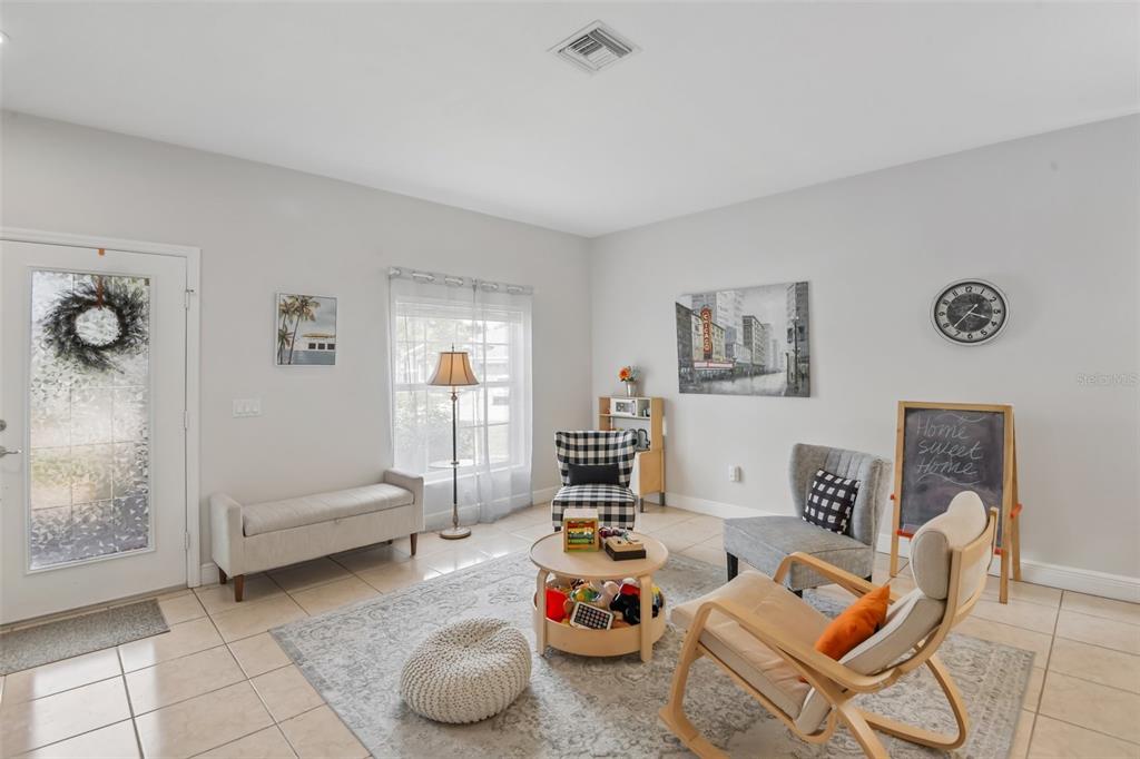 A living room features light tile flooring, a patterned area rug, and several seating options — 5903 CAPE LOOP, LAND O LAKES, FL