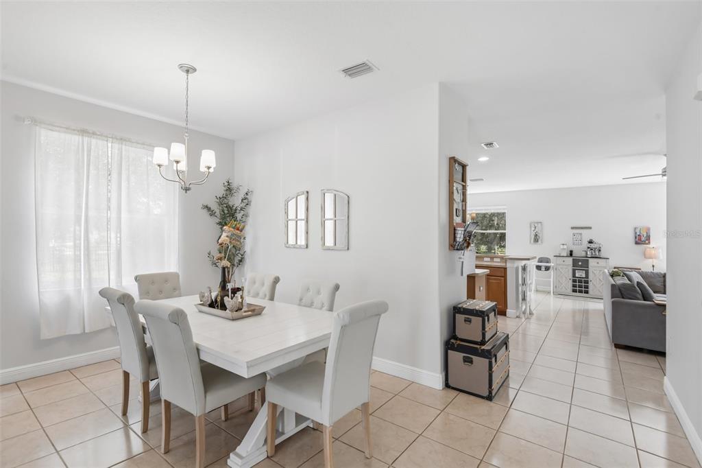 A dining area with a white table and chairs sits adjacent to an open living room — 5903 CAPE LOOP, LAND O LAKES, FL