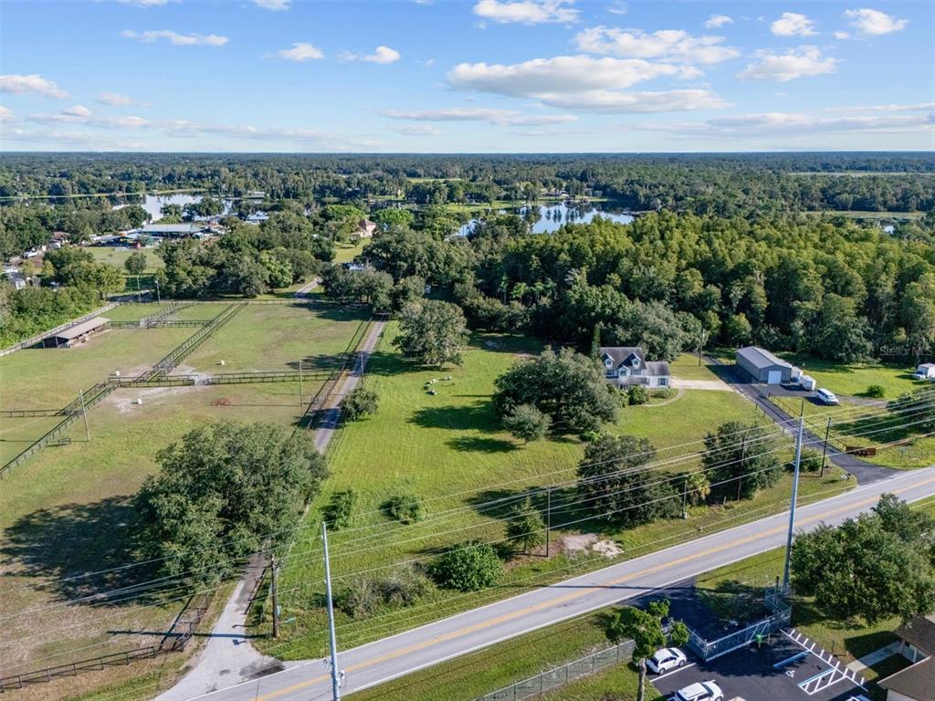 An aerial view shows a house, a large barn, fenced pastures, and a nearby lake — 0 MILAM DRIVE, ODESSA, FL