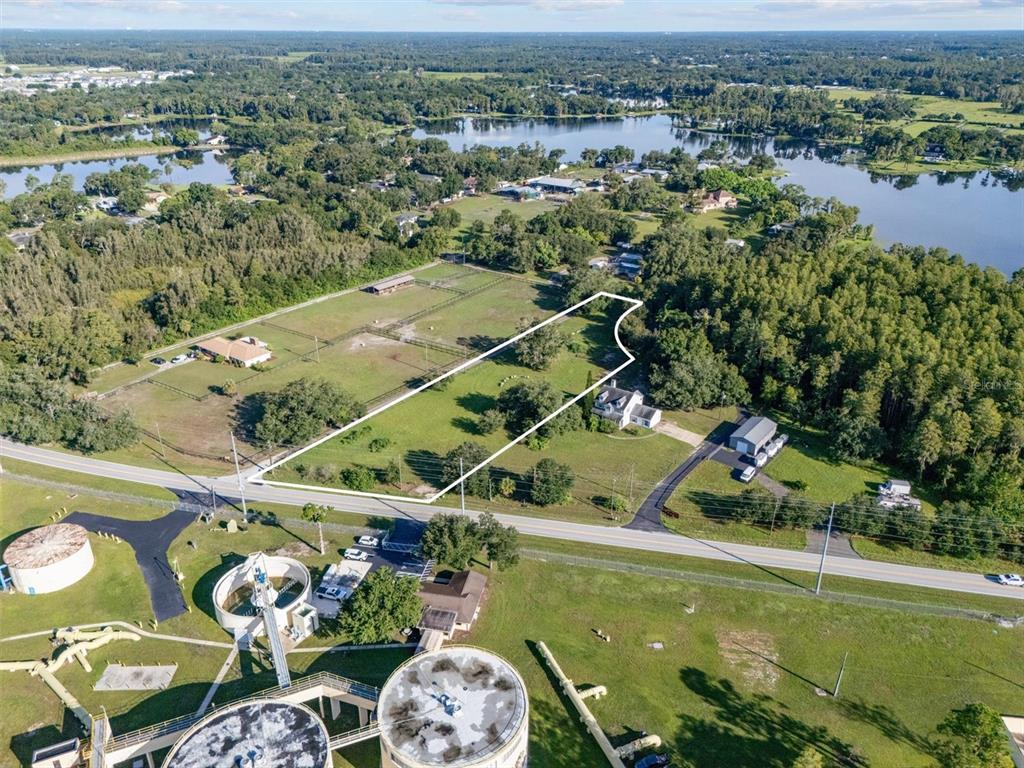 An aerial view shows a fenced residential property outlined in white near a water treatment facility — 0 MILAM DRIVE, ODESSA, FL