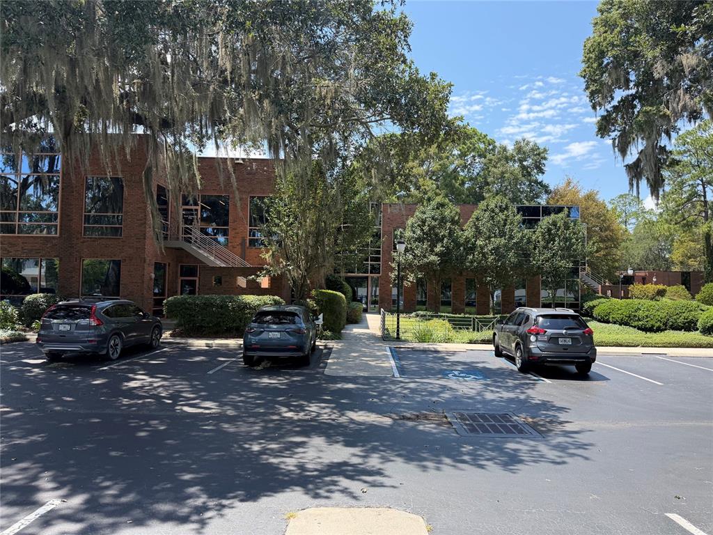 A two-story brick office building sits behind a parking lot with three parked cars — 2700 NW 43RD STREET UNIT C, GAINESVILLE, FL