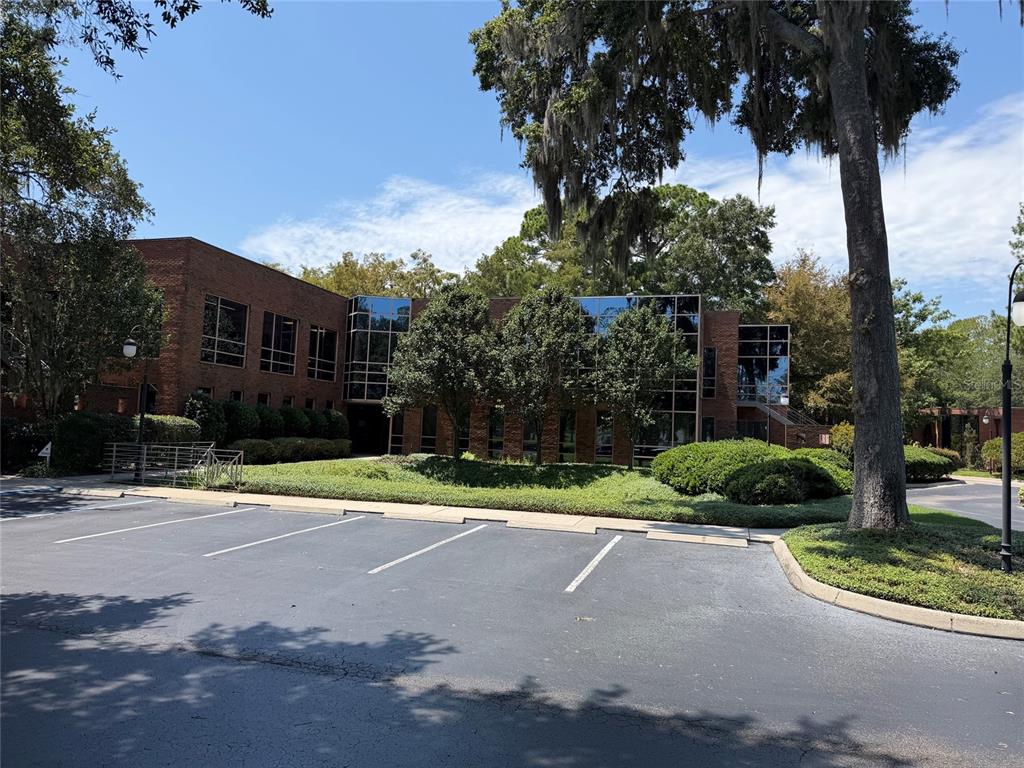 A two-story brick office building with large windows sits behind a paved parking lot — 2700 NW 43RD STREET UNIT C, GAINESVILLE, FL