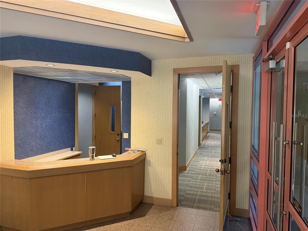 A reception desk sits in front of a blue wall next to an open doorway — 2700 NW 43RD STREET UNIT C, GAINESVILLE, FL