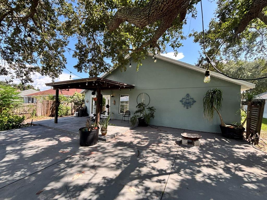 A backyard patio features a covered porch, concrete flooring, and mature trees providing shade — 6473 LONG BREEZE ROAD, ORLANDO, FL